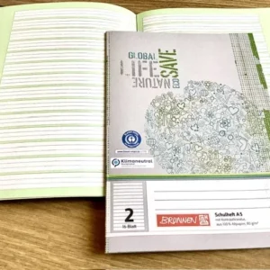 aufgeschlagenes A5-Schulheft mit der Lineatur 2 fürs 2. Schuljahr mit grünem Kontrasthintergrund. Umweltfreundlicher Schulbedarf bei Polly Paper in Berlin-Mitte