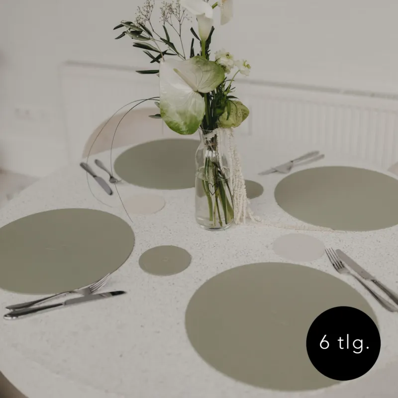 Gedeckter Tisch mit grünen Platzsets und passenden Untersetzern in Grün.