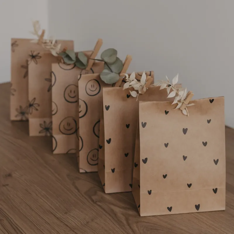 Geschenkbeutel aus Kraftpapier mit schwarzem Herzmuster, dekorativ gefaltet und mit Trockenblumen verziert